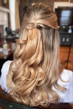 a woman with long blonde hair sitting in a chair and wearing a half - up braid