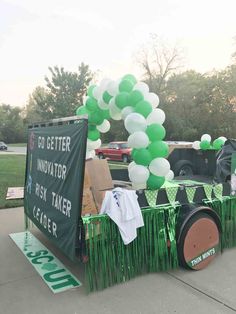 a green and white truck decorated with balloons