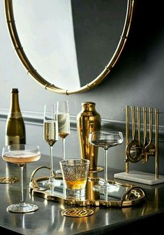 an assortment of wine glasses and champagne bottles on a table in front of a mirror