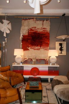 a living room filled with lots of furniture next to a painting on the wall above a coffee table