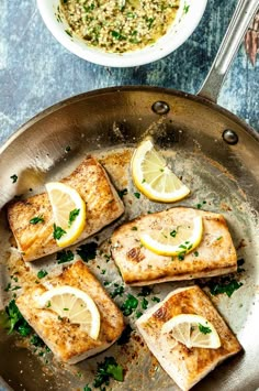 four fish fillets in a pan with lemons and parsley on the side