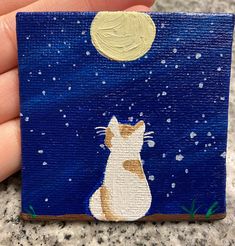 a painting of a cat sitting on top of a blue surface with the moon in the background