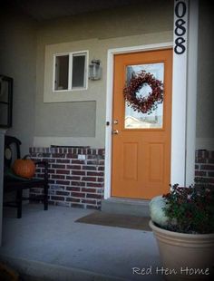 an orange front door with a wreath on it