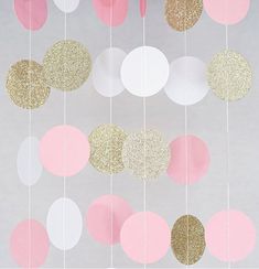 pink and gold confetti hanging from strings on a white wall with silver background