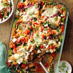 a glass casserole dish filled with pasta and veggies on a wooden table