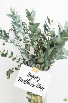 a vase filled with greenery and a sign that says happy mother's day