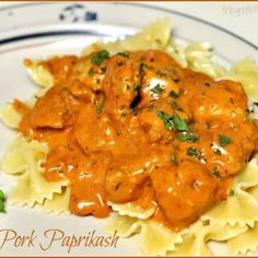 a white plate topped with pasta and meat covered in gravy on top of it