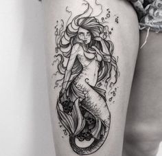 a black and white photo of a woman's leg with a mermaid tattoo on it