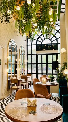 a restaurant with tables, chairs and plants hanging from the ceiling