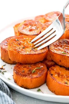 a fork is being used to cut up some pineapple upside down cakes on a white plate