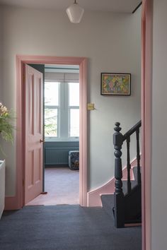 an open door leading to a hallway with pink walls and carpeting on the floor