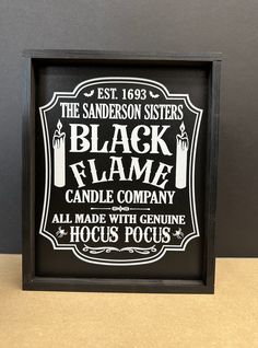 the black flame candle company sign is displayed in a wooden frame on a countertop