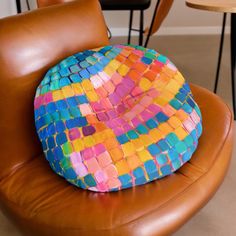 a colorful cushion sitting on top of a brown leather chair