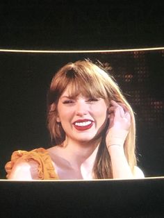 a woman with her eyes closed and mouth wide open on the television screen, holding her head to her ear