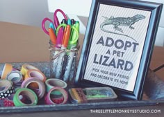 there is a jar full of pens and scissors next to a sign that says adopt a lizard