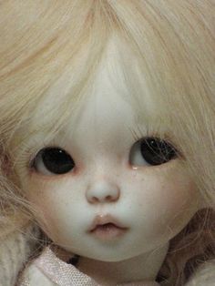 a close up of a doll with blonde hair