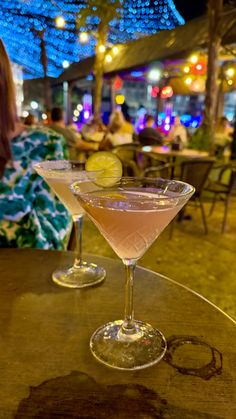 two martinis sitting on top of a table in front of a woman at a restaurant