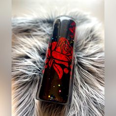 a black and red lighter sitting on top of a furry surface