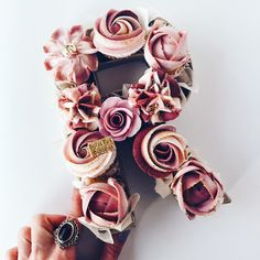 a person is holding some cupcakes with flowers on them in front of a white background