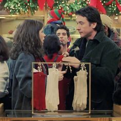 a group of people standing around each other in front of christmas decorations and stockings on display