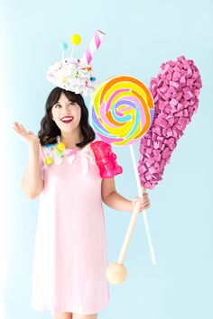 a woman holding two lollipops in her hands and wearing a birthday hat