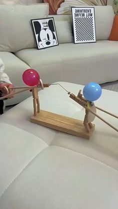 two people playing with balloons on top of a white table in front of a couch