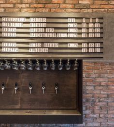 a row of beer taps in front of a brick wall