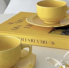 a yellow cup and saucer sitting on top of a book