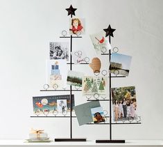 a christmas tree made out of photos on a white wall with black stars and frames