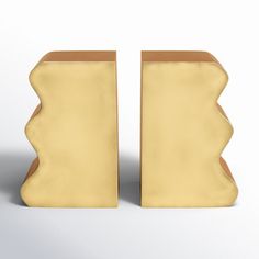 two yellow vases sitting next to each other on a white surface, one with brown edges