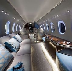 the inside of an airplane with lots of seats and couches on both sides of the aisle