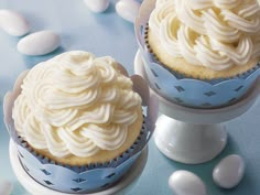 two cupcakes with white frosting sitting on top of each other next to an egg holder