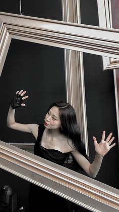 a woman is standing in front of a mirror with her hand up to the side