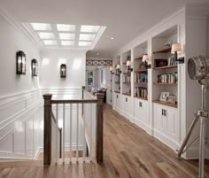 an empty room with white walls and wooden floors is pictured in this image, there are several bookshelves on either side of the wall