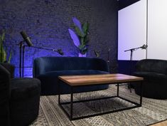 a living room with two couches and a table in front of a brick wall