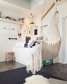 a hammock hanging from the ceiling in a room with white furniture and rugs