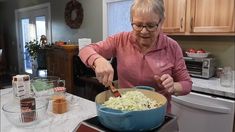 an older woman is preparing food in her kitchen with a large bowl on the stove