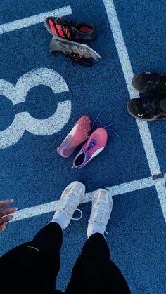 several pairs of shoes are sitting on the blue tennis court with white lines painted on it