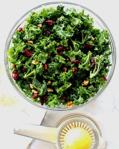 a bowl filled with greens and nuts next to a lemon