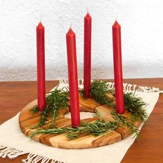 four red candles sitting on top of a wooden board