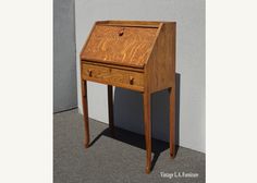 a small wooden desk sitting on top of a cement floor next to a white wall