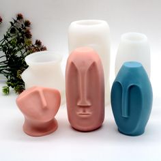 three different colored vases sitting next to each other on a white surface with flowers in the background