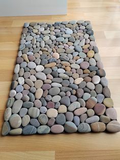 a rug made out of rocks is on the floor in front of a wall and hardwood floors