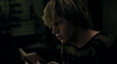 a young man reading a book in the dark