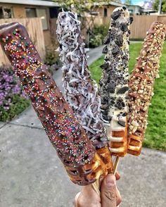 someone is holding up three different kinds of ice cream sticks with sprinkles on them