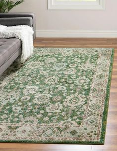 a living room area with a couch and rug on the floor, in front of a window