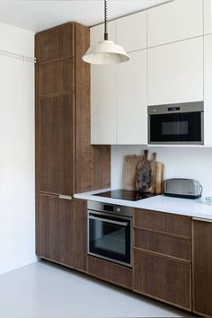 a kitchen with wooden cabinets and white counter tops, an oven, microwave and toaster