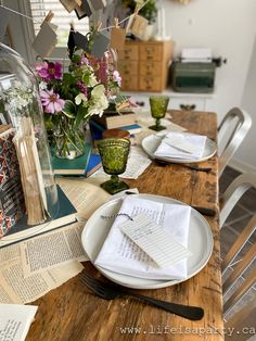 a wooden table topped with plates and napkins next to a vase filled with flowers