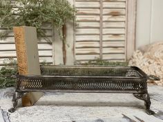 a book is sitting in a metal tray on a table next to a plant and bookshelf