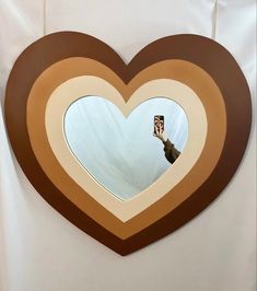 a heart shaped window with a hand holding a camera in the middle and a person taking a photo